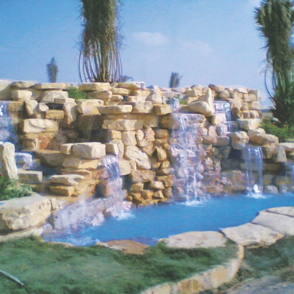 شلالات مائية تتدفق من الصخور إلى بركة صغيرة في منظر طبيعي.