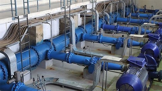 أنابيب ضخ كبيرة باللون الأزرق في محطة معالجة المياه مع محركات كهربائية.