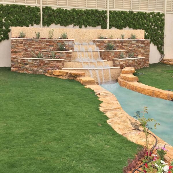 حديقة تحتوي على شلالات مائية وصخور طبيعية مع مساحات خضراء واسعة.